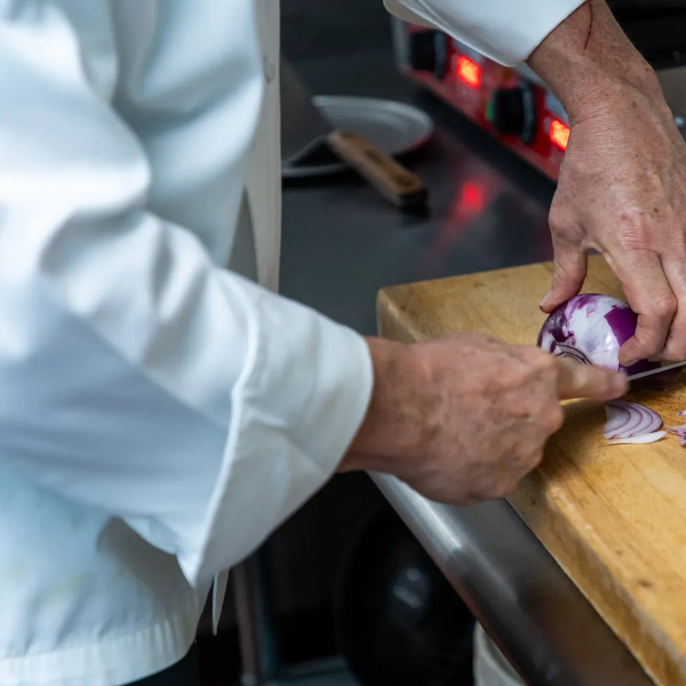 Knife work on the butcher block, slicing red onion